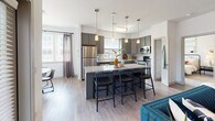 Located in Midlothian, VA, this well-appointed single-floor residence offers a thoughtfully designed open-concept layout with modern finishes throughout. The kitchen is a standout feature, showcasing gray and teal-toned cabinetry, granite countertops, stainless steel appliances, subway tile backsplash, and a large center island with bar seating — all illuminated by pendant lighting and hardwood-style flooring. The kitchen flows naturally into the living area, which is bright and airy thanks to multiple windows with plantation blinds and sheer draping. A dedicated dining space accommodates a full-size table and benefits from generous natural light through oversized windows. The residence includes multiple bedrooms, each finished with plush carpeting and ceiling fans or ample lighting. Bedrooms feature large windows with outdoor views and sufficient space for varied furniture arrangements, including one room with a built-in desk area suited for home office use. The bathrooms are finished with granite-topped vanities, gray cabinetry, and hardwood-style flooring. One bathroom features a dual-sink vanity and a soaking tub, while the second offers a clean, efficient layout. Consistent use of neutral tones, quality fixtures, and natural light gives the entire space a cohesive, modern aesthetic.