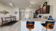 Located at 2132 Falcon Village Ln in Pflugerville, TX, this thoughtfully designed one-bedroom, two-bathroom residence offers a functional and stylish single-floor layout. Light wood-style flooring flows throughout the open-concept living area, creating a cohesive and airy feel.

The kitchen is a standout feature, equipped with a full suite of stainless steel appliances including a refrigerator, range, microwave, and dishwasher. Rich dark cabinetry with granite-style countertops provides ample storage and prep space, while a peninsula with bar seating connects seamlessly to the dining and living areas. Track lighting overhead adds both function and style.

The living room is bright and inviting, anchored by French doors that open to an outdoor area and allow natural light to fill the space. A ceiling fan overhead adds comfort to the room.

The spacious primary bedroom features herringbone-patterned flooring, a ceiling fan, and multiple windows that bring in generous natural light. The en-suite bathroom offers a dual-sink vanity with dark cabinetry and granite countertops. A dedicated laundry closet with a full-size washer and dryer adds everyday convenience. A dedicated closet rounds out this well-equipped residence.