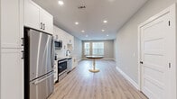 Located at 421 W Tremont Ave in Charlotte's vibrant South End neighborhood, this well-appointed one-bedroom, one-bathroom residence offers a thoughtfully designed single-floor layout with modern finishes throughout. Light-toned luxury vinyl plank flooring flows seamlessly across the entire unit, complementing the soft gray walls and crisp white trim.

The open-concept kitchen and living area serves as the heart of the home. The kitchen is outfitted with white shaker cabinetry, quartz countertops, a classic white subway tile backsplash, and a full suite of stainless steel appliances including a range, over-the-range microwave, dishwasher, and refrigerator. Matte black hardware adds a contemporary accent throughout. Recessed lighting brightens the space, while a window at the far end of the living area allows natural light to fill the room.

The generously sized primary bedroom offers a quiet retreat with ample floor space and neutral finishes. An attached walk-in closet features wire shelving systems, providing organized storage. The full bathroom includes a white vanity with quartz countertop, a large framed mirror, and a tub-shower combination with white subway tile surround. A dedicated laundry area houses a stacked full-size GE washer and dryer for added convenience.