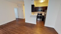 This single-floor residence offers a thoughtfully designed layout with rich, dark hardwood flooring and crisp crown molding that runs throughout, lending a polished, cohesive feel to every room. The kitchen is a functional highlight, featuring dark espresso cabinetry, sleek white countertops, a stainless steel undermount sink, and a full suite of stainless steel appliances including a range, over-the-range microwave, and refrigerator. A peninsula counter provides a natural transition between the kitchen and the open living area, enhancing the sense of flow and space. The living areas are bright and open, with neutral walls that complement the warm tones of the hardwood floors. The bedrooms are generously proportioned, each offering multiple windows that invite natural light and frame urban cityscape views. One bedroom features dual mirrored sliding closet doors, maximizing both storage and the sense of space. Two bathrooms serve the residence: one appointed with large-format white tile, a glass-enclosed walk-in shower, and brushed nickel fixtures; the other featuring a combination tub and shower with white subway tile, a wide vanity, and a full-width mirror. Additional storage is accessible via a dedicated closet off the main hallway, completing this well-organized and attractively finished home.