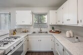 Located at 530 W First St in Tustin, California, this 2-bedroom, 1-bathroom single-story home offers a practical and functional layout with a clean, neutral aesthetic throughout. Wood-look laminate flooring runs continuously across all living areas, lending a cohesive and low-maintenance finish to the space.

The living room is bright and open, featuring large windows with vertical blinds that allow generous natural light to filter in. It connects seamlessly to the dining area and kitchen, creating an open-concept flow ideal for everyday living. The kitchen is well-equipped with white cabinetry, light speckled countertops, a double-basin sink, a gas range, and ample storage. A peninsula counter defines the boundary between the kitchen and dining space.

Both bedrooms are comfortably sized with wood-look flooring, vertical blind-covered windows, and ceiling fans with integrated lighting. Three closets throughout the unit provide notable storage capacity. A hallway connects the bedrooms to the shared full bathroom, which includes a tiled tub-shower combination, a pedestal sink, and a small frosted window for ventilation and light.

The home's neutral gray-toned walls and consistent flooring create a calm, move-in-ready environment suited for a range of living arrangements.
