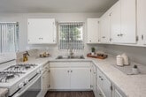 Located at 530 W First St in Tustin, California, this 2-bedroom, 1-bathroom single-story home offers a practical and functional layout with a clean, neutral aesthetic throughout. Wood-look laminate flooring runs continuously across all living areas, lending a cohesive and low-maintenance finish to the space.

The living room is bright and open, featuring large windows with vertical blinds that allow generous natural light to filter in. It connects seamlessly to the dining area and kitchen, creating an open-concept flow ideal for everyday living. The kitchen is well-equipped with white cabinetry, light speckled countertops, a double-basin sink, a gas range, and ample storage. A peninsula counter defines the boundary between the kitchen and dining space.

Both bedrooms are comfortably sized with wood-look flooring, vertical blind-covered windows, and ceiling fans with integrated lighting. Three closets throughout the unit provide notable storage capacity. A hallway connects the bedrooms to the shared full bathroom, which includes a tiled tub-shower combination, a pedestal sink, and a small frosted window for ventilation and light.

The home's neutral gray-toned walls and consistent flooring create a calm, move-in-ready environment suited for a range of living arrangements.