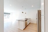 Located at 3001 Leavenworth St in Omaha, Nebraska, this efficiently designed unit offers a thoughtful, open-concept layout that maximizes its compact footprint. The combined kitchen and living area serves as the heart of the space, showcasing light hardwood-style flooring, crisp white walls, and abundant natural light streaming through large windows with roller shades. A ceiling fan adds both function and style to the living area.

The kitchen is a standout feature, centered around a peninsula island with a dark stone countertop, undermount sink, and stylish pendant lighting. White shaker-style cabinetry reaches toward the ceiling for ample storage, complemented by a subway tile backsplash and a full suite of stainless steel appliances, including a refrigerator, range, and microwave.

The bathroom is clean and functional, featuring a tub/shower combo with a curved curtain rod, a white vanity with a stone-topped counter, and matching hardwood-style flooring. A dedicated laundry area houses a stacked washer and dryer unit alongside a wire storage shelf, offering convenient in-unit functionality. The overall aesthetic is modern and neutral, creating a bright and welcoming atmosphere throughout.