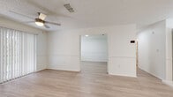 Located at 1918 Plantation Key Cir in Brandon, FL, this single-story home offers a bright, clean interior finished throughout with light wood-look flooring and a crisp, neutral color palette. The open layout connects living and adjacent areas seamlessly, with ceiling fans, textured ceilings, and chair-rail-style wall molding adding subtle architectural detail to the main living spaces. Large sliding glass doors in the living area invite natural light and provide views of the surrounding greenery, while vertical blinds offer privacy and light control.

The kitchen is well-appointed, featuring light wood cabinetry, white countertops, a peninsula for additional prep and serving space, stainless steel appliances including a refrigerator, range, and dishwasher, and overhead fluorescent lighting for ample task illumination. A dedicated utility area conveniently houses a full-size washer and dryer alongside additional cabinetry and a utility sink.

The bedrooms are generously proportioned, each featuring the same light flooring, wall molding details, and windows fitted with horizontal blinds that allow for natural light. The bathroom includes a single-sink vanity with light wood cabinetry and white countertops, a toilet, and a tub-shower combination with tile surround. Throughout the home, the consistent finishes and open flow create a cohesive and functional living environment.