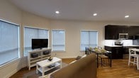 Located at 36 Pine St in Poughkeepsie, NY, this two-bedroom, two-bathroom residence offers a thoughtfully designed single-floor layout. The open-concept living and dining area serves as the heart of the home, featuring warm hardwood flooring, clean white walls, and recessed lighting that creates a bright and inviting atmosphere. Multiple windows fitted with roller shades allow natural light to fill the space while maintaining privacy. The living area provides ample room for comfortable seating and entertainment, flowing seamlessly into a dedicated dining space ideal for everyday meals or hosting guests. The clean, neutral color palette throughout lends a modern and versatile aesthetic that complements a variety of interior styles. The efficient floor plan makes excellent use of the available space, ensuring that both bedrooms and bathrooms are comfortably accessible. This residence strikes a balance between functional design and comfortable living, making it a practical choice for those seeking a well-maintained home in the Poughkeepsie area.
