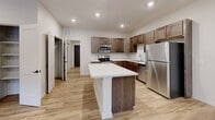 Located at 1220 W Highland Blvd in Lincoln, Nebraska, this single-story, 2-bedroom, 1-bathroom home offers a thoughtfully designed layout with modern finishes throughout. The open-concept kitchen and living area serves as the heart of the home, featuring rich walnut-toned cabinetry, marble-look quartz countertops, a center island, and a full suite of stainless steel appliances. Light luxury vinyl plank flooring runs throughout the main living areas, complementing the neutral wall tones and recessed lighting. The living room receives natural light through multiple windows and a glass-panel entry door. Both bedrooms offer clean lines and light flooring, with the primary bedroom accompanied by a spacious walk-in closet outfitted with multi-level shelving and rods. The full bathroom includes a tub-shower combo, a single vanity with quartz countertop, and wood-toned cabinetry. A dedicated laundry room provides full-size washer and dryer hookups along with upper cabinetry for added storage. The attached garage features a concrete floor and an automatic opener, providing secure and convenient parking. A connecting interior space offers additional utility. This home combines practical functionality with contemporary design in a clean, move-in-ready package.