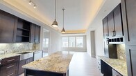 Located in the heart of Uptown Dallas at 2212 McKinney Ave, this well-appointed one-bedroom, two-bathroom residence offers a refined urban living experience. Light wood flooring flows throughout the open layout, complementing the neutral tones and clean lines that define the space's modern aesthetic.

The living room is bright and airy, featuring a distinctive tray ceiling with warm accent lighting and large windows that frame sweeping views of the Dallas skyline, filling the room with natural light. Access to a private balcony further enhances the connection to the vibrant cityscape outside.

The chef's kitchen is a standout feature, showcasing rich dark cabinetry, granite countertops with a matching backsplash, a generous center island with pendant lighting overhead, and a full suite of stainless steel appliances including a gas range, refrigerator with ice maker, microwave, and dishwasher. A built-in desk area adds functional versatility.

The bedroom offers a comfortable retreat with city views, while a dedicated walk-in closet provides well-organized storage with custom shelving. Both bathrooms are finished with quality materials, with one featuring a glass-enclosed shower and granite vanity surfaces. The overall ambiance is polished and contemporary, ideal for those seeking a sophisticated urban lifestyle.