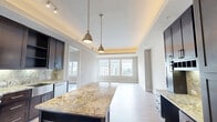 Located in the heart of Uptown Dallas at 2212 McKinney Ave, this well-appointed one-bedroom, two-bathroom residence offers a refined urban living experience. Light wood flooring flows throughout the open layout, complementing the neutral tones and clean lines that define the space's modern aesthetic.

The living room is bright and airy, featuring a distinctive tray ceiling with warm accent lighting and large windows that frame sweeping views of the Dallas skyline, filling the room with natural light. Access to a private balcony further enhances the connection to the vibrant cityscape outside.

The chef's kitchen is a standout feature, showcasing rich dark cabinetry, granite countertops with a matching backsplash, a generous center island with pendant lighting overhead, and a full suite of stainless steel appliances including a gas range, refrigerator with ice maker, microwave, and dishwasher. A built-in desk area adds functional versatility.

The bedroom offers a comfortable retreat with city views, while a dedicated walk-in closet provides well-organized storage with custom shelving. Both bathrooms are finished with quality materials, with one featuring a glass-enclosed shower and granite vanity surfaces. The overall ambiance is polished and contemporary, ideal for those seeking a sophisticated urban lifestyle.