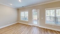 Located at 120 Buck Island Rd in Bluffton, SC, this two-story, 3-bedroom, 2-bathroom home offers a well-organized layout spread across two floors. The main level features an open-concept kitchen and living area with warm hardwood-style flooring throughout. The kitchen is appointed with crisp white shaker cabinets, a herringbone tile backsplash, stainless steel appliances, and a central island with a sink and pendant lighting — ideal for both cooking and entertaining. A ceiling fan complements the living area, and a wood-railed staircase connects the floors with classic charm. The main level also includes an attached garage with an automatic opener and concrete flooring. Upstairs, the primary bedroom features a walk-in closet and an en suite bathroom with a double-sink vanity and a glass-enclosed shower. Two additional bedrooms are carpeted, each with ceiling fans and windows that bring in natural light. One bedroom features a distinctive shiplap accent wall with hardwood-style flooring. A full hallway bathroom with a shower-tub combo serves the secondary bedrooms. Crown molding, clean white trim, and a neutral color palette give the home a cohesive, move-in-ready aesthetic throughout.