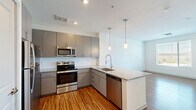 Located at 26800 North 27th Avenue in Phoenix, AZ, this well-designed one-bedroom, one-bathroom unit offers a thoughtfully efficient floor plan across a single level. The open-concept kitchen and living area serves as the heart of the home, showcasing warm wood-style flooring, sleek gray cabinetry, a classic white subway tile backsplash, and a full suite of stainless steel appliances including a range, microwave, and dishwasher. A peninsula with granite countertops and an undermount sink provides additional prep space and casual seating, while modern pendant lighting adds a contemporary touch overhead. The living area flows naturally from the kitchen, offering a bright, versatile space. The bedroom features soft carpeting underfoot, neutral white walls, a ceiling fan, and a sliding glass door that opens to a private balcony with open views of the surrounding landscape. The bathroom is finished with consistent granite countertops on gray cabinetry, a large vanity mirror, and a full tiled shower-tub combo with chrome fixtures. Clean white walls and recessed lighting contribute to a crisp, modern ambiance throughout the entire unit.