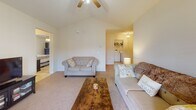Located at 901 Falls Park Dr in Sanford, NC, this single-floor home offers a well-designed layout with a comfortable, functional flow throughout. The living room is a standout space, featuring a striking vaulted ceiling with a ceiling fan that amplifies the sense of openness. Soft carpet underfoot and access to natural light through a windowed door contribute to a welcoming atmosphere. The galley-style kitchen is efficiently designed with warm oak cabinetry, crown molding, light tile flooring, and white appliances including a refrigerator, range, microwave, and dishwasher. Adjacent to the kitchen, the dining area is brightened by a large window with blinds and pendant lighting overhead. Two carpeted bedrooms provide comfortable retreats, each with ceiling fans and windows that allow natural light. The primary bathroom features warm wood cabinetry, a single vanity, tile flooring, and a shower-tub combination. A second full bathroom mirrors the same practical design. An in-unit laundry area, visible from the living space, adds everyday convenience. Throughout, the home maintains a neutral, light-toned palette that creates a clean and inviting ambiance.