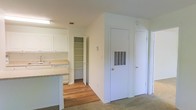 Located at 3500 Creighton Rd in Pensacola, Florida, this single-floor residence offers a practical and well-organized layout designed for comfortable everyday living. The kitchen is outfitted with white cabinetry that extends to the upper walls, providing generous storage space, along with light-toned countertops and a built-in sink. A kitchen island or peninsula adds additional workspace and helps define the transition between the kitchen and adjacent living areas. A dedicated walk-in pantry off the kitchen offers substantial shelving, making it ideal for organized storage of pantry goods and household essentials. The flooring throughout the space features a combination of warm hardwood in the kitchen and dining areas, transitioning to plush carpet in the living and hallway spaces, adding a sense of comfort underfoot. The walls are finished in a clean, neutral white throughout, contributing to a bright and open atmosphere. A hallway leads to additional rooms, with multiple doors suggesting private spaces such as bedrooms or utility closets. HVAC venting is integrated into the wall, reflecting a thoughtfully planned interior. Overall, the space presents a clean, move-in ready environment well-suited for functional residential living in the Pensacola area.
