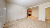 Located in Sherwood, Oregon, this 2-bedroom, 1-bathroom residence offers a functional and well-designed single-floor layout. The open-concept living area features neutral-toned carpet and flows seamlessly into the kitchen, which is finished with warm wood cabinetry, granite countertops, and light tile flooring. The galley-style kitchen is efficiently organized with ample upper and lower cabinet storage, recessed lighting, and black appliances including a range, dishwasher, and refrigerator. The living area is bright and welcoming, with natural light entering through a window adjacent to the front entry door, which features a glass panel for additional daylight. Both bedrooms are carpeted and finished in soft neutral tones. The primary bedroom includes a wide sliding closet, a ceiling fan, and a generously sized window that fills the room with natural light and views of the surrounding greenery. The second bedroom also features a closet and natural light from a corner window. The bathroom mirrors the design of the kitchen with matching wood cabinetry, granite countertops, a single vanity with a large mirror, and tile flooring. Throughout, the space maintains a clean, consistent aesthetic with white trim, neutral walls, and a practical layout suited for comfortable everyday living.