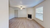 This single-floor, two-bedroom, two-bathroom residence in Austin, Texas offers a well-organized layout with consistent design choices throughout. The living area serves as the heart of the home, featuring light wood-look flooring, a textured ceiling, and a ceiling fan that enhances air circulation. A tile-surround fireplace anchors the room, adding warmth and a focal point to the space. Natural light enters through multiple windows fitted with blinds, while a sliding glass door opens onto a private balcony, extending the living space outdoors.

The kitchen connects to the living area via a pass-through counter with dark cabinetry and granite-style countertops, providing a functional and open feel. Appliances including a stovetop, microwave, and refrigerator are present, alongside ample cabinetry for storage.

Both bathrooms feature tub-shower combinations finished with large-format marble-look tile surrounds, lending a clean and polished aesthetic. Each bedroom offers wood-look flooring, a ceiling fan, and natural light from windows. One bedroom includes a walk-in closet with built-in shelving on both sides, maximizing storage capacity. A second bedroom also provides closet access. Throughout the unit, neutral tones and consistent finishes create a cohesive, move-in-ready atmosphere.