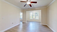 Located at 5001 Ballantyne Drive in Simpsonville, SC, this single-floor, one-bedroom, one-bathroom home offers a functional and well-designed layout. The living room features light wood-look flooring, crown molding, and a ceiling fan, with a large window that fills the space with natural light and offers outdoor views. Adjacent to the living room, the combined dining area is finished with tile flooring, chair rail molding, and an elegant chandelier, and opens directly into the kitchen. The kitchen is equipped with rich warm-toned wood cabinetry, granite-look countertops, a double stainless steel sink, and black appliances including a range and refrigerator. The bedroom is a comfortable size, featuring the same wood-look flooring, a pendant light fixture, and a window overlooking the outdoors. The full bathroom includes tile flooring, a shower/tub combination, and ample wall space. A dedicated laundry room provides washer and dryer hookups with built-in shelving overhead. A separate closet offers additional storage. Crown molding and consistent neutral tones throughout create a cohesive, clean aesthetic across the entire home.