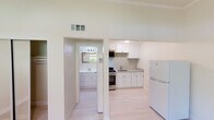 This single-floor space offers a clean, modern aesthetic throughout, defined by light hardwood flooring and warm, neutral wall tones that create an airy and welcoming atmosphere. Crown molding adds a refined architectural touch to each room.

The kitchen is a standout feature, showcasing white shaker-style cabinetry, granite countertops, and a matching granite tile backsplash that extends the full length of the cooking wall. Stainless steel appliances include a gas range with oven, an over-the-range microwave, and a full-size refrigerator, making it a fully equipped and functional cooking space.

The main living area is generously proportioned, bathed in natural light from a large window that frames a lush green outdoor view. A ceiling fan provides comfort, and the open, unobstructed layout offers excellent flexibility for furniture arrangement.

The bedroom is a calm, understated space with the same light hardwood flooring and crown molding, complemented by a mirrored sliding closet that enhances the sense of space.

The bathroom retains a classic character, featuring a tiled tub-and-shower combination with warm terracotta and deep red accent tiles, paired with brushed nickel fixtures and a towel bar for a practical yet stylish finish. A window in the bathroom allows for natural light and ventilation.