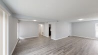 This single-floor residence in Baton Rouge, Louisiana presents a well-organized and thoughtfully designed layout with two bedrooms and two full bathrooms. The expansive main living area features wood-look luxury vinyl plank flooring in a warm gray tone, neutral light gray walls, white baseboards, and a textured ceiling — creating a clean, contemporary aesthetic throughout. The open layout connects the living space to the rest of the unit, with clear sightlines to the hallway and kitchen beyond.

The kitchen is a standout feature, offering a U-shaped configuration with dark gray shaker-style cabinetry, white countertops, a stainless steel sink, and black appliances including an electric range. A window above the sink provides natural light, making the kitchen both functional and inviting.

Both bedrooms are well-proportioned, featuring the same wood-look flooring, soft gray walls, and windows that bring in natural light. One bedroom includes mirrored sliding closet doors, adding depth and brightness to the room.

The two bathrooms are finished in a consistent style, each equipped with a tub-shower combination. One bathroom features a dark-toned vanity with a white countertop and a window for natural ventilation, while the second is clean and efficiently laid out. The overall ambiance is bright, neutral, and move-in ready.
