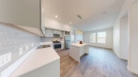Located at 9110 W Tropicana in Las Vegas, NV, this well-appointed 2-bedroom, 2-bathroom unit offers a thoughtfully designed single-floor layout. The open-concept living area seamlessly connects the kitchen, dining, and living spaces, creating an airy and functional environment bathed in natural light from large windows.

The modern kitchen is a standout feature, showcasing soft gray shaker-style cabinetry, crisp white quartz countertops, a subway tile backsplash, and a full suite of stainless steel appliances including a gas range, built-in microwave, dishwasher, and refrigerator. A central island provides additional prep space and casual seating. Warm wood-look flooring flows throughout the main living areas, complementing the bright, neutral palette.

Both bedrooms are carpeted and generously sized, with the primary bedroom offering ample closet space. The two bathrooms are finished with wood-look tile flooring, white vanities with quartz countertops, and large mirrors. One bathroom features a soaking tub and shower combo, while the second includes a walk-in shower. An in-unit laundry area adds everyday convenience. With four closets and two hallways, storage is plentiful throughout this clean, contemporary Las Vegas residence.