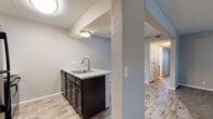 Located at 2323 North Woodlawn Boulevard in Wichita, Kansas, this single-floor residence offers a well-appointed layout with a blend of updated finishes and classic architectural details. The open-concept living area is a standout feature, anchored by a striking floor-to-ceiling brick fireplace with a raised hearth that adds warmth and character to the space. Plank-style flooring flows through the main living and kitchen areas, complemented by neutral-toned carpet in the bedrooms and living room. A ceiling fan overhead enhances comfort throughout the main living space.

The kitchen is thoughtfully designed with dark espresso cabinetry, light granite-style countertops, black appliances including a range and overhead microwave, and a peninsula with a sink that opens to the living area — ideal for everyday convenience. Textured ceilings are present throughout the home, adding a classic touch.

The bedrooms are generously sized, each featuring plush carpet flooring, neutral paint tones, and windows with blinds that allow natural light to filter in. The bathrooms are equipped with matching dark cabinetry, granite-style vanity tops, and chrome fixtures. One bathroom features a walk-in shower stall, while another includes a toilet, vanity, and grab bar for added accessibility. A hallway connects the private spaces, completing this functional and updated single-floor layout.