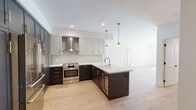 Located in the heart of Los Angeles, this thoughtfully designed single-floor residence blends contemporary style with high-end finishes throughout. The open-concept kitchen is a true centerpiece, showcasing a two-tone cabinet scheme with dark lower cabinetry and lighter upper cabinets, all accented by sleek brass hardware. A large island with a built-in wine cooler and sink anchors the space, while pendant lighting adds warmth overhead. Premium stainless steel Bosch appliances — including a French door refrigerator, built-in wall oven, microwave, and gas range with a stainless hood — complete this chef-caliber kitchen, all set atop wide-plank light hardwood flooring that flows seamlessly throughout the home. The bedrooms are bright and airy, featuring large black-framed windows that frame views of the surrounding neighborhood and allow generous natural light. The primary bathroom impresses with a floating double-vanity in warm wood tones, a backlit mirror spanning the full width of the counter, matte black fixtures, and a separate water closet. A second bathroom features a soaking tub with striking deep-blue vertical tile, a glass partition, and matte black hardware. A powder room with a bold dark accent wall rounds out the well-appointed bathrooms. Clean white walls, recessed lighting, and black door hardware create a cohesive modern aesthetic throughout.