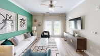 Located in Summerville, SC, this well-appointed 2-bedroom, 2-bathroom single-story home offers a thoughtfully designed layout across a comfortable footprint. The open-concept kitchen and living area serves as the heart of the home, featuring dark espresso cabinetry, light quartz countertops, a subway tile backsplash, stainless steel appliances, and light wood-style flooring. A kitchen island with seating provides additional functionality, while the adjoining living room impresses with crown molding, a ceiling fan, and French doors that invite natural light and outdoor views. A bold green accent wall adds a distinctive design touch to the living space. The primary bedroom is generously sized with soft carpet, natural light from a large window, and access to a private en-suite bathroom complete with a dual-sink vanity, dark wood cabinetry, and light tile flooring. The primary closet features wrap-around wire shelving for ample storage. The second bedroom is equally comfortable, also featuring carpet and natural light. A dedicated laundry room houses a full-size washer and dryer with overhead wire shelving. A connecting hallway ties the layout together efficiently, making this home as practical as it is visually appealing.
