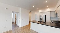 Located in Wildomar, CA, this single-story, 2-bedroom, 2-bathroom home offers a clean, modern design with a bright and cohesive aesthetic throughout. Light wood-style flooring runs continuously across every room, complementing the crisp white walls and creating a fresh, airy atmosphere.

The open-concept kitchen is a standout feature, showcasing floor-to-ceiling white cabinetry, a striking dark marble-style countertop, a subtle tile backsplash, and a full suite of stainless steel appliances including a refrigerator with ice maker, range, microwave, and dishwasher. A peninsula with an undermount sink and matte black faucet provides additional prep space and connects seamlessly to the living area.

The spacious primary bedroom features a ceiling fan, natural light through slatted blinds, and direct access to a well-appointed en-suite bathroom. The primary bath is finished with matching dark stone countertops and a walk-in glass-door shower with clean white tile surround. A generously sized walk-in closet with built-in shelving and hanging rods adds practical storage.

The second bedroom also includes a ceiling fan and a bright window with outdoor views. Both bedrooms and living areas benefit from recessed lighting. A hallway connects the main living spaces to the bedrooms, maintaining a functional and efficient layout throughout the home.