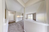 This two-story home at 7099 Granada Dr offers a well-organized layout spread across two floors, plus a full basement, providing a generous amount of living space throughout. The main floor welcomes you through a dedicated entrance that flows into an open living and dining area. The living room features plush carpeting, a ceiling fan, and a sliding glass door that opens directly to a private patio with outdoor views, allowing natural light to fill the space. The kitchen is designed with a pass-through counter connecting to the living area, light wood-toned cabinetry with contrasting dark upper accents, a double sink, electric range, and hardwood-style flooring. A hallway connects the kitchen to the main entrance and closet storage areas. The upper floor houses the bedroom, which features carpet flooring, a natural-light window with blinds, and a built-in double closet. The full bathroom includes a vanity with a large mirror and an elegant multi-light fixture. Additional closets are distributed throughout for ample storage. The unfinished basement offers substantial open space with a painted concrete floor, exposed joists, utility sink, and HVAC systems, presenting excellent storage or utility potential. The home also includes a dedicated utility room and two staircase access points.