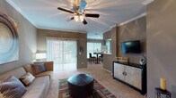 This single-floor residence offers a thoughtfully designed layout that balances comfort and functionality. The living room serves as the heart of the home, featuring warm carpeting, crown molding, a ceiling fan with light fixture, and sliding glass doors with vertical blinds that invite natural light and outdoor views. The space flows seamlessly into a dining nook enclosed by large windows, filling the area with abundant natural light and garden views.

The kitchen is equipped with light wood cabinetry, white appliances including an electric range and dishwasher, white countertops, a stainless steel double sink, and hardwood-style flooring — offering both practicality and a clean aesthetic.

Two well-sized bedrooms provide comfortable retreats, each carpeted and featuring windows with views of the surrounding greenery. The primary bedroom benefits from a bay window configuration that enhances its sense of space and light, while the second bedroom includes its own window with outdoor views.

Both bathrooms are finished consistently, featuring light wood vanity cabinetry, white countertops, tile flooring, a tub-shower combination with a curtain, and overhead cabinetry for additional storage. The warm, neutral color palette used throughout the residence creates a cohesive and inviting atmosphere from room to room.