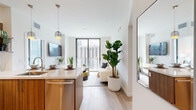 Located at 225 SW Tenth St in Miami's vibrant Brickell district, this modern residence offers four bedrooms and two bathrooms across a thoughtfully designed single-floor layout. The open-concept living and kitchen area serves as the heart of the home, featuring light hardwood-style flooring, clean white walls, and an abundance of natural light streaming through expansive floor-to-ceiling sliding glass doors that frame impressive Miami skyline views. The kitchen is outfitted with warm wood cabinetry, stainless steel appliances, a white quartz waterfall island with bar seating, and pendant lighting. An in-unit stacked washer and dryer is conveniently tucked nearby. The living area opens directly to city views, creating a seamless indoor-outdoor feel. The primary bedroom includes direct balcony access through floor-to-ceiling glass doors, offering stunning high-rise views, while additional bedrooms feature large windows with equally captivating cityscapes. The primary bathroom boasts a sleek walk-in glass shower with white subway tile, while the second bathroom offers a tub-shower combination with modern wood vanity and LED-lit mirror. The overall ambiance is contemporary and light-filled, with a clean, minimalist aesthetic throughout.