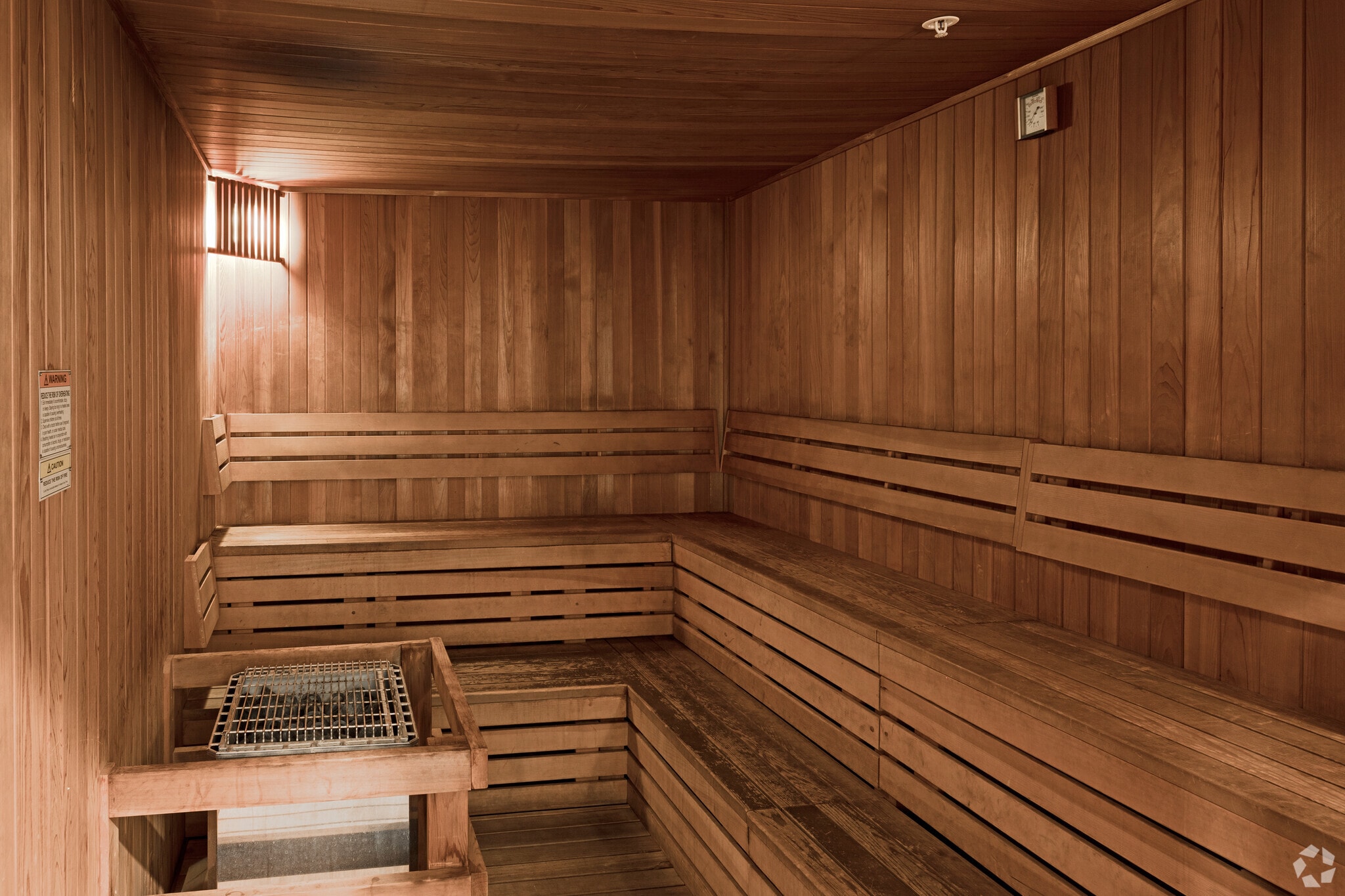 Interior of a clean wooden sauna with tiered seating and a sauna heater.