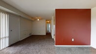 Located at 14801 Bowie Road in Laurel, Maryland, this single-floor unit offers a practical and comfortable layout across several well-defined living spaces. The living room is a standout area, featuring plush carpeting, a ceiling fan, a bold terracotta accent wall, and floor-to-ceiling vertical blinds that open to outdoor views and allow generous natural light to fill the room. A separate, more expansive carpeted area—likely a second living or dining space—features large sliding glass doors dressed with vertical blinds, further enhancing the sense of openness and connection to the outdoors. The kitchen is equipped with warm honey-toned wood cabinetry, dark granite-style countertops, a gas range, and tile flooring, providing a functional cooking environment. The bedrooms are carpeted and bright, with windows offering natural light and outdoor views. One bedroom includes a built-in closet with bifold doors and overhead shelving, providing practical storage. The bathroom features a pedestal sink, a tub and shower combination with floor-to-ceiling tile surround accented by a decorative mosaic border, and a mirrored medicine cabinet. Throughout, neutral wall tones create a clean, versatile backdrop.
