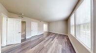 This 540 square foot apartment in Presidential Greens offers a surprisingly spacious layout with three bedrooms and one bathroom. The interior showcases a blend of modern amenities and practical design. The kitchen is a standout feature, boasting dark wood cabinetry, stainless steel appliances, and a sleek countertop. A large window above the sink allows natural light to flood the space.

Throughout the apartment, wood-style flooring adds warmth and durability, while neutral-toned walls create a blank canvas for personalization. The primary bedroom, measuring 220 square feet, is generously sized and includes carpeting for added comfort. Other bedrooms, while smaller, offer versatility for various uses.

The bathroom features clean white tiles and modern fixtures, maintaining the apartment's contemporary feel. Large windows in the bedrooms and living areas not only brighten the space but also offer views of the surrounding area. The open layout between the kitchen and living area enhances the sense of spaciousness, making this compact apartment feel larger than its actual square footage suggests.