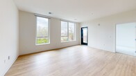 Located at 8530 W National Ave in West Allis, WI, this well-appointed 2-bedroom, 2-bathroom unit offers a thoughtfully designed layout with modern finishes throughout. The open-concept kitchen and living area serves as the heart of the space, anchored by a central island with a white quartz countertop, an undermount sink, and pendant lighting overhead. The kitchen features warm wood cabinetry that extends to the ceiling, a white subway tile backsplash, and a full suite of stainless steel appliances, including a range, microwave, and refrigerator. Light hardwood flooring flows throughout the main living areas, complementing the bright, neutral color palette. Large floor-to-ceiling windows in the living area flood the space with natural light and offer pleasant outdoor views of the surrounding greenery. Both bedrooms are carpeted and well-sized, each with large windows that continue the theme of natural light and outdoor connectivity. The primary bedroom is generously proportioned with ample room for furnishings. The primary bathroom features a dual-sink vanity with wood cabinetry, white countertops, and a large mirror, while the second bathroom includes a soaking tub and matching wood-toned vanity. A dedicated closet and private entry door with direct outdoor access complete this clean, contemporary residence.