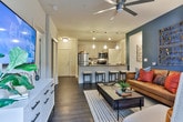 This single-floor residence in Newnan, Georgia, showcases a thoughtfully designed open-concept layout that seamlessly connects the kitchen, dining, and living areas. The kitchen serves as a central hub, anchored by a large island with granite countertops, an undermount sink, and bar seating for multiple guests. Light wood cabinetry pairs with stainless steel appliances, including a range, microwave, and refrigerator, while pendant lighting adds a modern, decorative touch overhead. Dark hardwood-style flooring flows throughout the main living areas, contrasting elegantly with the neutral cabinetry and walls.

The living room features a striking teal accent wall, a ceiling fan, and large windows with access to an outdoor area, filling the space with natural light. Two bedrooms offer comfortable retreats; the primary bedroom includes its own accent wall and ample natural light, while the second bedroom features plush carpeting and generous window views.

Both bathrooms are finished with granite-topped vanities and wood-toned cabinetry. The primary bathroom includes a glass-enclosed walk-in shower, while the secondary bathroom offers a full tub-shower combination with neutral tile surrounds. Throughout the residence, consistent design choices create a cohesive, contemporary ambiance.