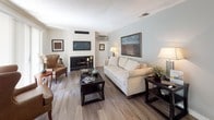 Located at 2400 Harbor Blvd in California, this single-floor residence offers a thoughtfully designed layout that balances comfort and practicality. The living area is bright and welcoming, featuring wood-look flooring, neutral toned walls, and a large sliding glass door fitted with vertical blinds that opens to a view of lush greenery outside, filling the room with natural light. A fireplace unit serves as a focal point, complemented by ample space for seating and entertainment.

The dining area flows naturally from the living space, featuring a ceiling fan with integrated lighting and a pass-through connection to the kitchen, creating an open and airy feel. The galley-style kitchen is well-equipped with stainless steel appliances including a gas range, microwave, and refrigerator, alongside white cabinetry and sparkling quartz countertops with a double-basin sink.

The bathroom is clean and functional, showcasing a wide quartz vanity countertop with white cabinetry, a large wall mirror, wood-look flooring, and a shower-tub combination. Framed artwork adds a finishing touch to the space. Throughout the home, consistent wood-look flooring ties the rooms together, creating a cohesive and modern aesthetic.