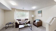 Located at 10897 48th Ave in Allendale, MI, this multi-floor home offers four bedrooms, five bathrooms, and a well-organized layout spread evenly across three floors. The open kitchen and living area anchor the main level, where warm-toned hardwood flooring flows through the kitchen. Honey-toned cabinetry, ample counter space, and a full suite of white appliances — including a refrigerator, range, and over-the-range microwave — make the kitchen functional and practical. A breakfast bar with seating provides a casual dining option adjacent to the living space. The living room features plush carpeting and a large window that invites natural light and outdoor views, creating a comfortable gathering space. A wall-mounted TV area adds a dedicated media zone. Each bedroom is carpeted and offers a calm, neutral palette; select rooms include built-in shelving and storage units integrated around the bed frame for efficient use of space. Multiple windows in the bedrooms ensure natural light. The five bathrooms are consistently finished with warm wood-toned vanities, white countertops, and walk-in shower stalls. Two closets and three hallways contribute to the home's practical flow. Staircases connect each floor seamlessly throughout this well-appointed Allendale residence.