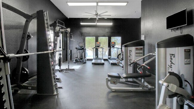 Moderno gimnasio con equipos de ejercicio de última generación, que incluyen cintas de correr y máquinas de pesas en un espacio de gimnasio elegante y bien iluminado. - Advenir at The Meadows
