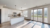 This thoughtfully designed one-bedroom, one-bathroom residence at 41 N Rangeline Rd offers a modern aesthetic with clean lines and contemporary finishes throughout its efficiently arranged single-floor layout. The kitchen serves as a centerpiece of the home, showcasing a large quartz-topped island with an undermount sink and matte black faucet, crisp white shaker cabinetry extending to the ceiling, subway tile backsplash, stainless steel appliances including a French door refrigerator, and pendant lighting overhead. Light wood-look flooring runs throughout the main living and kitchen areas, lending a warm, cohesive feel. The bedroom is a comfortable retreat featuring plush carpeting, a ceiling fan, and a window that invites natural light. It connects directly to a generously sized walk-in closet outfitted with wire shelving and hanging rods for ample storage. The full bathroom impresses with a dual-sink vanity topped with quartz counters, matte black hardware, a large mirror, tile flooring, and a glass-enclosed shower. A dedicated laundry area houses a full-size Whirlpool front-load washer and dryer with overhead shelving, adding everyday convenience. The overall ambiance is bright, clean, and modern.