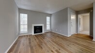 Located at 6001 Oakland Knoll Dr in Fort Worth, Texas, this single-story home offers a well-organized layout with a clean, updated aesthetic throughout. The living room serves as the heart of the home, showcasing warm wood-look flooring, neutral gray walls, a textured ceiling, and a white-surround fireplace flanked by multiple windows that allow generous natural light to fill the space. The open, airy feel of the living area is enhanced by its generous proportions and a welcoming front entry door.

The kitchen is efficiently designed in a galley style, featuring gray cabinetry, white countertops, a subway tile backsplash, and stainless steel appliances including a refrigerator, range, and dishwasher. A dedicated in-unit laundry area with a full-size washer and dryer is conveniently accessible directly from the kitchen.

The bedrooms are carpeted for comfort and each feature ceiling fans, large windows with outdoor views of surrounding greenery, and ample wall space. A hallway connects the bedrooms to a full bathroom equipped with a tub-shower combination. The home's consistent use of wood-look flooring in the main living areas and its neutral color palette create a cohesive, move-in ready environment throughout.