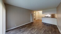 Located at 2401 S Hacienda Blvd in Hacienda Heights, California, this single-floor unit offers a clean, functional layout designed for comfortable everyday living. The living area is generously sized, finished with durable dark wood-style flooring and neutral-toned walls that create a bright, welcoming atmosphere. A wall-mounted air conditioning unit and a sliding glass door with vertical blinds provide both climate control and access to natural light. An adjoining area features plush carpeting and a wall vent, offering a versatile space well-suited for a bedroom or den. The kitchen is efficiently designed with white cabinetry, dark countertops, a stainless steel refrigerator, and a gas range, complemented by a chandelier overhead that adds a subtle decorative touch. A peninsula counter separates the kitchen from the dining area, enhancing the open-concept feel. The bathroom includes white vanity cabinetry with a dark countertop, a mirror, and a separate water closet housing a toilet and a full tub/shower combination. Throughout the unit, textured ceilings and wood-style flooring contribute to a cohesive, well-maintained aesthetic. White-trimmed doorways and clean wall finishes complete the polished, move-in-ready presentation of this Hacienda Heights residence.
