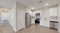 Located at 1720 Crestdale Dr in Houston, Texas, this single-story 2-bedroom, 2-bathroom home offers a clean, modern aesthetic throughout. Light wood-look flooring runs continuously across all rooms, creating a cohesive and airy feel. Neutral warm-gray walls complement the bright, open layout.

The kitchen is well-appointed with white shaker-style cabinetry, white quartz countertops, and a full suite of stainless steel appliances including a refrigerator, electric range, microwave, and dishwasher. The kitchen flows naturally into the living area, supporting an open-concept lifestyle.

Both bedrooms are comfortably sized with ceiling fans, recessed lighting, and windows fitted with white blinds that allow natural light while maintaining privacy. The primary bedroom includes access to a dedicated closet and an ensuite bathroom.

Each bathroom features tub-shower combinations with large-format marble-look tile surrounds, coordinating tile flooring, white vanity cabinetry, and quartz countertops finished with brushed bronze hardware — giving both bathrooms a polished, contemporary look.

The home also includes a dedicated closet for additional storage. Overall, the space presents a well-maintained, move-in-ready environment with consistent modern finishes and a functional single-floor layout suited for comfortable everyday living.