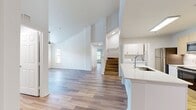 This two-story townhouse at MacAlpine Place offers a generous 1640 square feet of living space, with 1220 sq ft on the ground floor and 420 sq ft upstairs. The home boasts three bedrooms, including a 160 sq ft primary bedroom, and two full bathrooms. The open-concept design seamlessly integrates the kitchen and living room, creating an inviting space for entertaining and everyday living.

The kitchen is a highlight, featuring sleek light-colored cabinetry, stainless steel appliances, and a convenient island with a sink. Modern finishes include quartz countertops and a subway tile backsplash. Adjacent to the kitchen is a dedicated laundry area with full-sized appliances.

Throughout the home, warm-toned hardwood flooring adds a touch of elegance and continuity. The bathrooms are well-appointed with white vanities, large mirrors, and combination shower/tub units. Large windows in the living areas and bedrooms allow for ample natural light, while ceiling fans provide additional comfort.

Storage is plentiful with four closets throughout the home, including walk-in options. The property also features two staircases, likely leading to the upper floor bedrooms. Overall, this townhouse offers a contemporary living space with a practical layout and modern amenities, ideal for those seeking a low-maintenance yet stylish home.