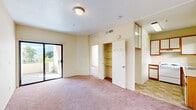 Located at 2500 Honolulu Ave in Glendale, CA, this two-bedroom, one-bathroom residence offers a practical and well-organized single-floor layout. Warm beige walls and soft pink carpeting run throughout the main living areas and bedrooms, creating a cohesive and neutral interior. The living area features a sliding glass door that opens to an outdoor balcony, bringing in natural light and providing views of the surrounding greenery. A dedicated closet with built-in shelving adds convenient storage just off the main living space. The primary bedroom is generously sized, featuring a large sliding-door closet with a hanging rail, a window with mountain views, and ample floor space. The second bedroom is similarly carpeted and includes its own window with pleasant outdoor views. The kitchen is compact yet functional, outfitted with wood-trimmed white cabinetry, a white electric range, a stainless steel sink, and checkered tile flooring that distinguishes it from the carpeted areas. The bathroom includes a white vanity with a large mirror and overhead lighting, offering a clean and simple aesthetic. Overall, the space presents a straightforward and livable layout well-suited for those seeking comfortable accommodations in the Glendale area.