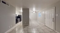 Located at 200 Primrose Cir in New Braunfels, TX, this single-story unit offers a clean, functional layout finished with neutral gray walls and light tile flooring throughout. The open living area is bright and airy, featuring a ceiling fan with light fixture and a window that allows natural light to fill the space. The layout flows seamlessly between the living area and the adjacent kitchen, which is equipped with white cabinetry, dark countertops, a double stainless steel sink, and black appliances including a refrigerator, range, and dishwasher. A structural column adds architectural definition between the kitchen and living spaces. The bedrooms are comfortably sized, each outfitted with ceiling fans and tile flooring. The primary bedroom includes access to a walk-in closet as well as an additional door, offering practical storage and convenience. The bathroom features a full tub-shower combination surrounded by large-format earth-toned tile accented with a decorative mosaic border, complemented by a small window for ventilation. Clean white trim and consistent finishes throughout the unit create a cohesive, low-maintenance living environment well-suited for everyday comfort in the heart of New Braunfels.