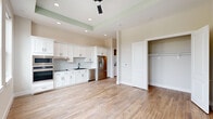 Located at 900 New Day Avenue in Montgomery, TX, this single-floor studio offers a well-designed open layout that makes efficient use of its intimate footprint. Wood-look tile flooring runs throughout the entire space, lending warmth and visual continuity from room to room.

The main living and kitchen area is bright and airy, anchored by a tray ceiling with a ceiling fan and recessed lighting. Large black-framed windows allow generous natural light to fill the space, offering views of the surrounding landscape. The kitchen features white shaker-style cabinetry, a classic tile backsplash, stainless steel appliances including a French door refrigerator, wall oven, microwave, and dishwasher, as well as a black matte sink fixture. A built-in open closet with a hanging rod is conveniently integrated into the main living area.

The bathroom is clean and modern, showcasing a walk-in shower with floor-to-ceiling marble-look tile surround and a black-framed glass enclosure, complemented by grab bars and a toilet. The overall color palette is light and neutral, with crisp white trim and soft warm-toned walls contributing to a fresh, contemporary ambiance throughout the space.
