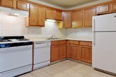 Located at 2966 Beach Rd in Port Huron, Michigan, this single-floor residence offers a practical and well-organized layout. The kitchen is a standout feature, equipped with warm honey-toned oak cabinetry extending from floor to ceiling, providing generous storage throughout. White appliances — including a gas range, dishwasher, and full-size refrigerator — complement the light-colored tile countertops and classic white tile backsplash. Light ceramic tile flooring runs throughout the kitchen, offering easy maintenance and a clean aesthetic. A bifold closet door adjacent to the kitchen adds convenient storage access. The living areas and bedrooms are finished with plush wall-to-wall carpeting in a neutral tone, creating a comfortable and cohesive feel. The bedroom features a large window dressed with vertical blinds, allowing natural light to filter in. A spacious living area includes a wide sliding glass door with vertical blinds, offering additional light and potential outdoor access. The bathroom is finished with white ceramic tile flooring and includes a tub and shower combination enclosed by sliding glass doors with chrome framing, a toilet, and a wood-toned vanity with a white countertop. The overall interior maintains a neutral color palette throughout, lending a clean and move-in-ready atmosphere.