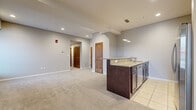 Located at 1 Canal Square Plaza in Akron, Ohio, this single-floor residence offers a well-designed open-concept layout with a seamless flow between the living, dining, and kitchen areas. The generously sized living space is carpeted throughout and illuminated by recessed lighting, with multiple windows fitted with blinds that allow for natural light while maintaining privacy.

The kitchen is outfitted with rich dark cabinetry, granite countertops, a stainless steel sink, and a full suite of stainless steel appliances including a refrigerator, microwave, dishwasher, and range. A peninsula island with pendant lighting extends into the living area, making it ideal for entertaining or casual dining. Tile flooring grounds the kitchen space.

The bedrooms are carpeted and bright, each featuring recessed lighting and windows with views to the exterior. One bedroom provides direct access to an adjacent space suitable for a walk-in closet or laundry area with tile flooring.

The bathroom is finished with large-format white tile flooring, a sleek dark vanity with a glass countertop and vessel sink, a framed mirror, and modern fixtures, presenting a clean and contemporary aesthetic throughout.