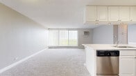 Located at 1417 Valley Lake Dr in Schaumburg, Illinois, this 2-bedroom, 1-bathroom residence offers a well-organized single-floor layout. The open-concept kitchen and living area serves as the heart of the home, featuring white cabinetry with brushed nickel hardware, white countertops, and stainless steel appliances including a dishwasher, range, and refrigerator. The kitchen is finished with durable hardwood-style flooring and flows seamlessly into the carpeted living area, which is brightened by a large floor-to-ceiling window with vertical blinds that invites generous natural light and offers pleasant outdoor views of the surrounding greenery.

Both bedrooms are carpeted and provide a calm, neutral atmosphere with baseboard heating and individual wall AC units. The primary bedroom is generously sized and includes a closet and a window overlooking the exterior. The second bedroom also features a large window with vertical blinds and ample natural light.

The bathroom is cleanly finished with light hardwood-style flooring, white subway tile surrounding the tub/shower combination, a white vanity with storage, and classic fixtures. A hallway connects the main living spaces efficiently. The overall aesthetic is clean, neutral, and move-in ready.