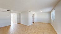 This single-floor residence offers a clean, open layout with a consistent design aesthetic carried throughout every room. Warm-toned ceramic tile flooring runs continuously across the entire space, contributing to a cohesive and easy-to-maintain interior. The living and common areas are generously proportioned, featuring crisp white walls, textured ceilings, and flush-mount lighting paired with well-placed HVAC vents for climate control.

The kitchen is a functional highlight, outfitted with bright white cabinetry accented by matte black hardware, light-toned countertops, and a stainless steel electric range with an overhead ventilation hood. A utility sink and ample upper and lower cabinet storage complete the workspace.

The bedrooms are bright and airy, each benefiting from windows that invite natural light and offer views of lush outdoor greenery, including palm trees visible from one room. Ceiling fans provide additional comfort, and louvered closet doors add a classic, practical touch.

The bathroom is finished in a clean, modern style with a full tub and shower combination, a white vanity with an integrated sink, and a framed mirror — all accented with matte black fixtures that tie the design together. Overall, this space presents a well-maintained, move-in ready layout with a light, neutral palette throughout.