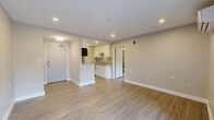 This efficiently designed 1-bedroom, 2-bathroom unit offers a clean, modern aesthetic throughout its single floor. Light-toned luxury vinyl plank flooring flows continuously across the open-concept living area, creating a cohesive and bright atmosphere complemented by recessed lighting and neutral gray walls with crisp white trim.

The entrance opens directly into a spacious living area, where a wall-mounted mini-split system provides climate control. Sliding glass doors invite natural light and offer direct access to a private balcony with outdoor views. The kitchen is thoughtfully integrated into the layout, featuring white shaker-style cabinetry, granite countertops, a stainless steel sink, and a full suite of stainless steel appliances including a refrigerator, electric range, and over-the-range microwave.

The bedroom is a well-proportioned retreat with a dedicated window, a wall-mounted mini-split, and an open closet alcove for storage. A hallway connects the primary bathroom, which includes a granite-topped vanity with an undermount sink and a walk-in tiled shower with a glass enclosure. The second bathroom features a glass-enclosed shower stall with tile surround and wood-look flooring. The unit is completed by a functional entrance and hallway that enhance the overall flow of the space.